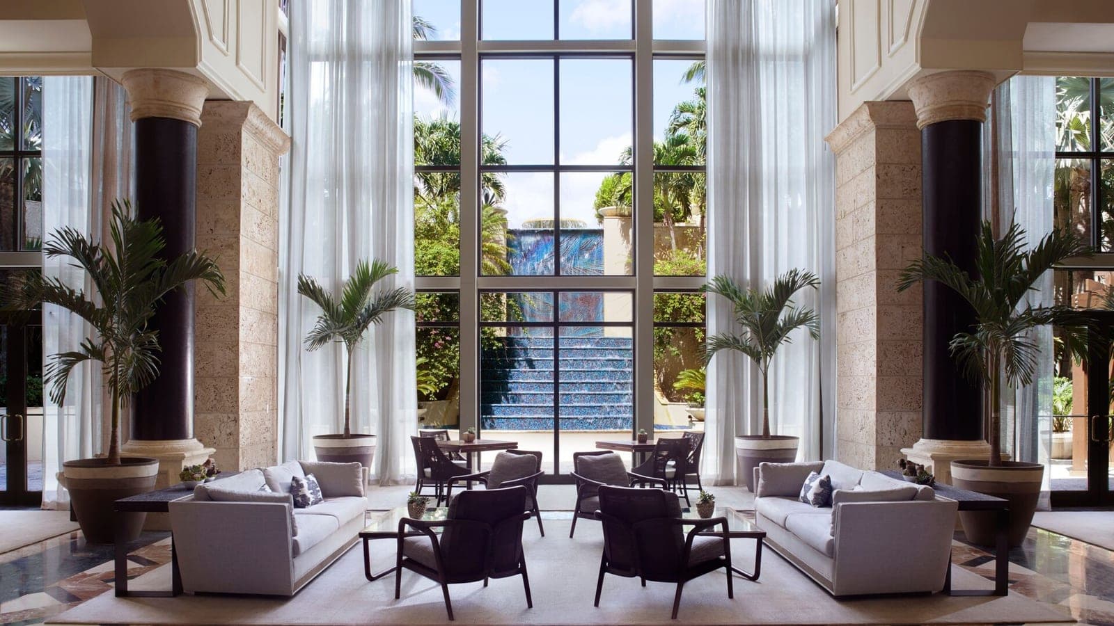 Lobby de The Ritz-Carlton Coconut Grove con ventanales hacia la fuente